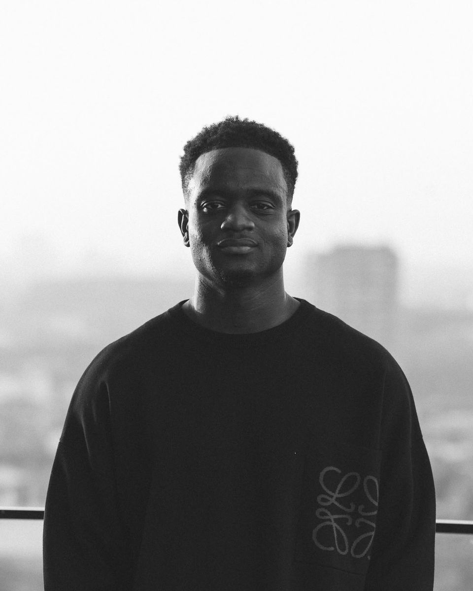 Keith Asare, Founder and CEO of AthletiQ, standing above a city skyline